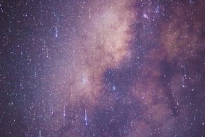 A breathtaking view of the Milky Way galaxy with an array of twinkling stars and vibrant celestial formations. Streaks of light suggest a meteor shower, creating a dynamic and mesmerizing effect against the vast backdrop of space.