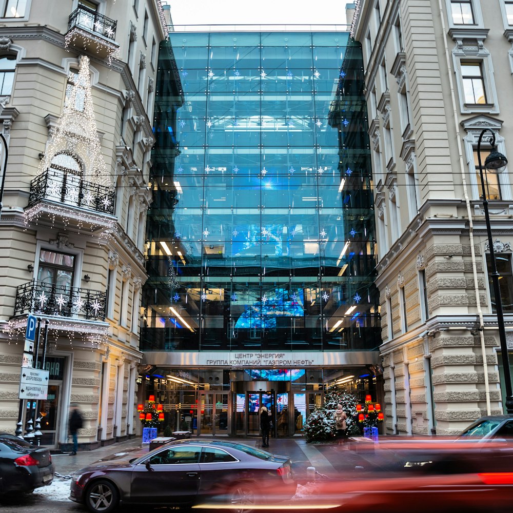 a car driving past a tall building with a lot of windows