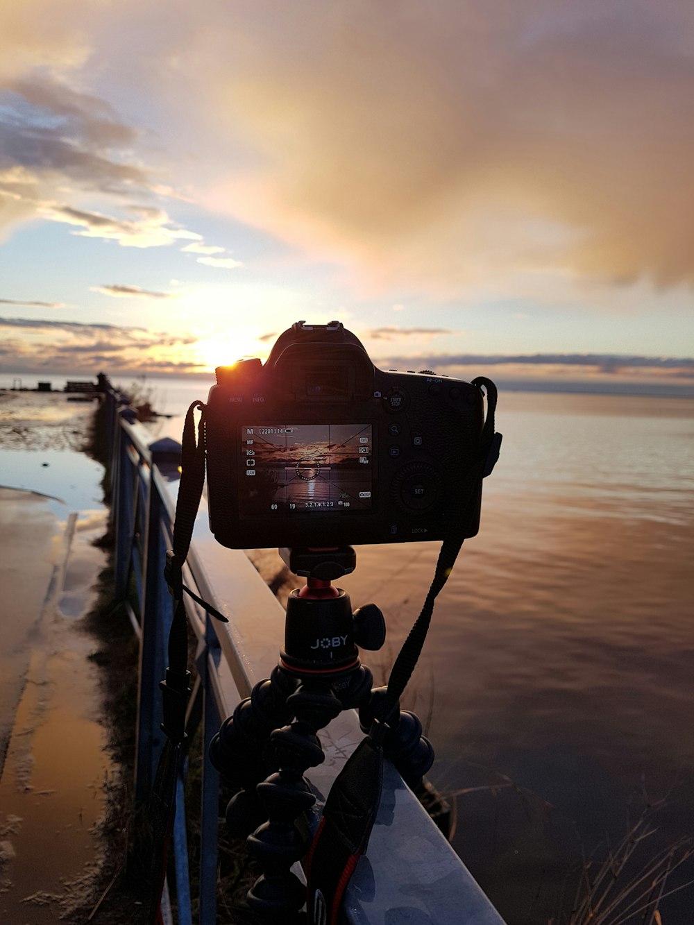 a camera sitting on top of a tripod next to a body of water