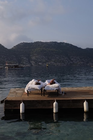 a couple of people laying on top of a wooden dock