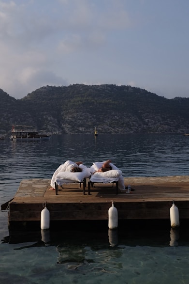 a couple of people laying on top of a wooden dock