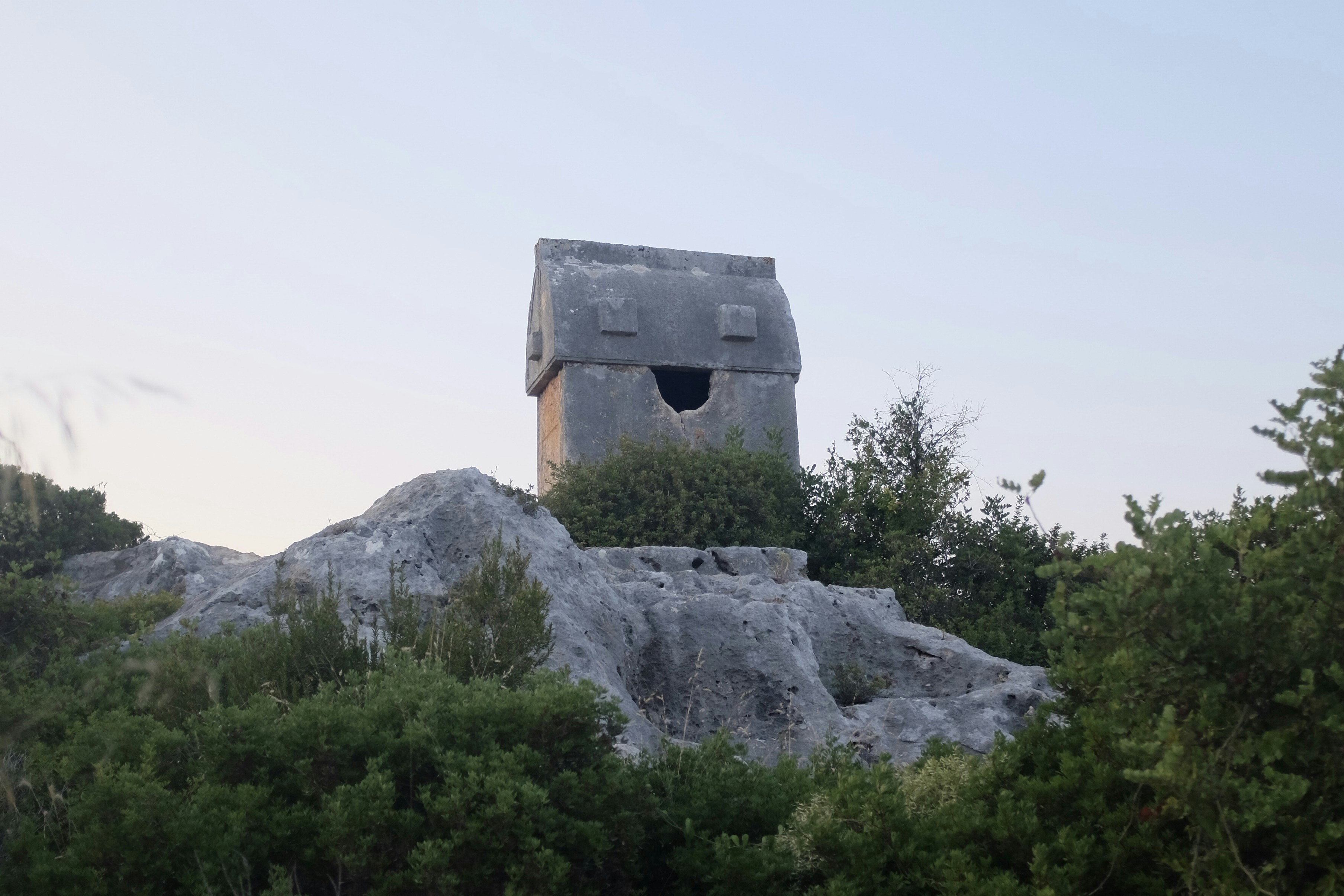 a stone structure on top of a hill surrounded by trees