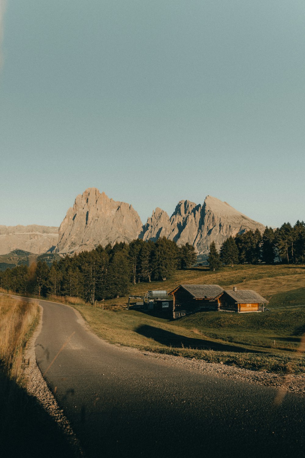 a road in the middle of a field with mountains in the background