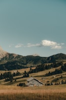 Rustic American-style barn under a clear blue sky surrounded by green hills.