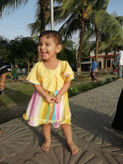 A cheerful toddler playing in colorful, soft cotton clothes outdoors.