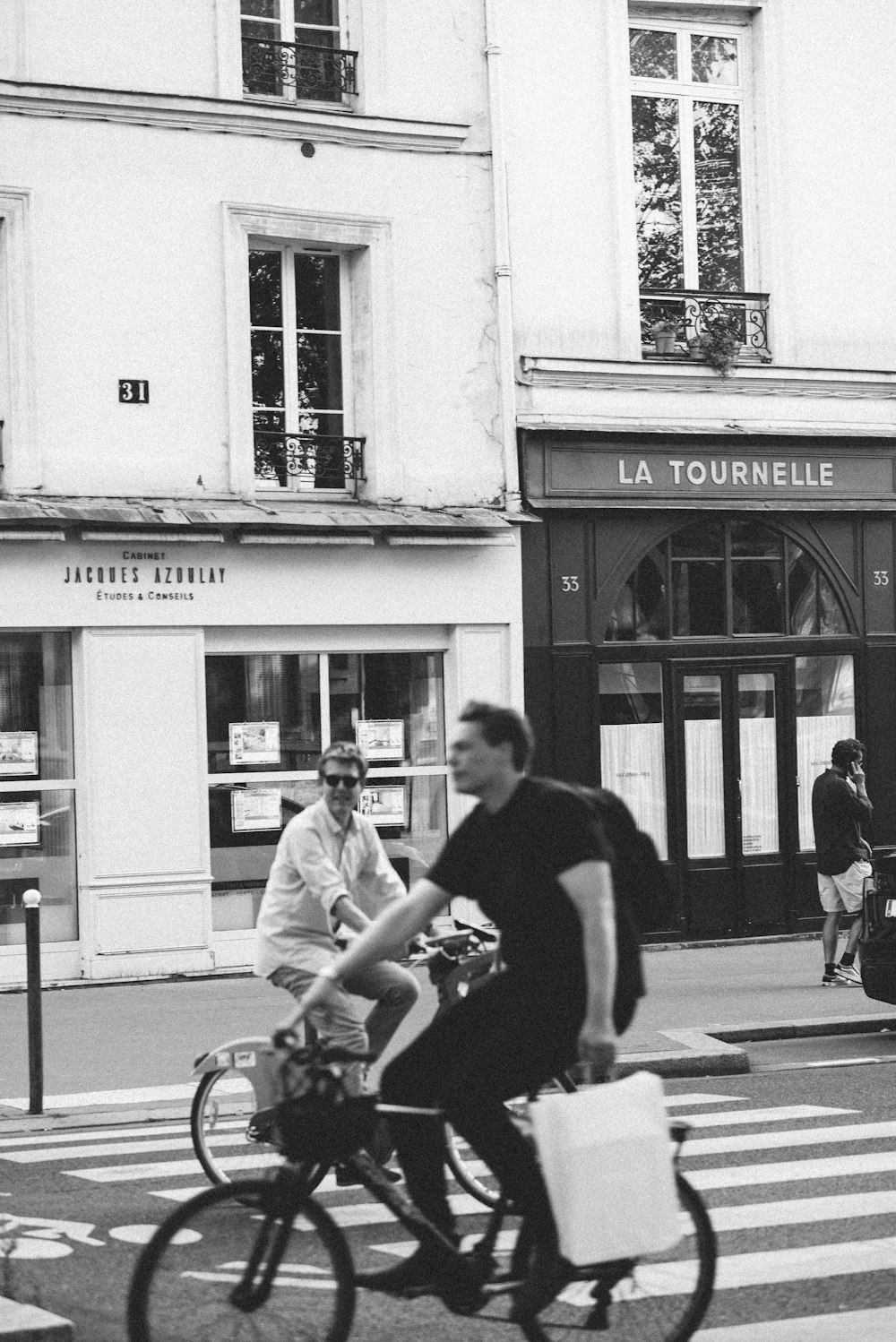 a man riding a bike down a street next to a tall building