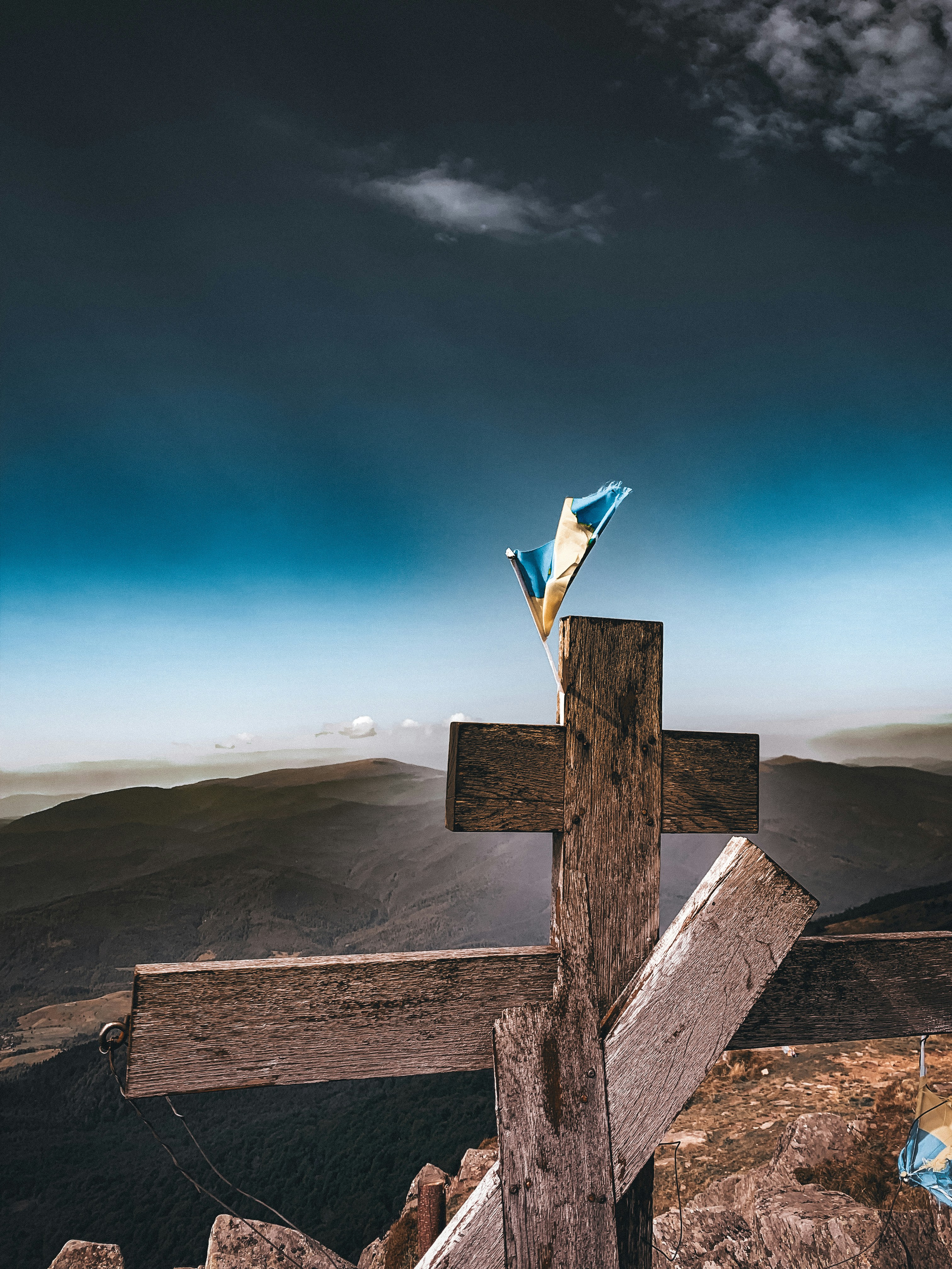 a wooden cross on top of a mountain under a cloudy sky