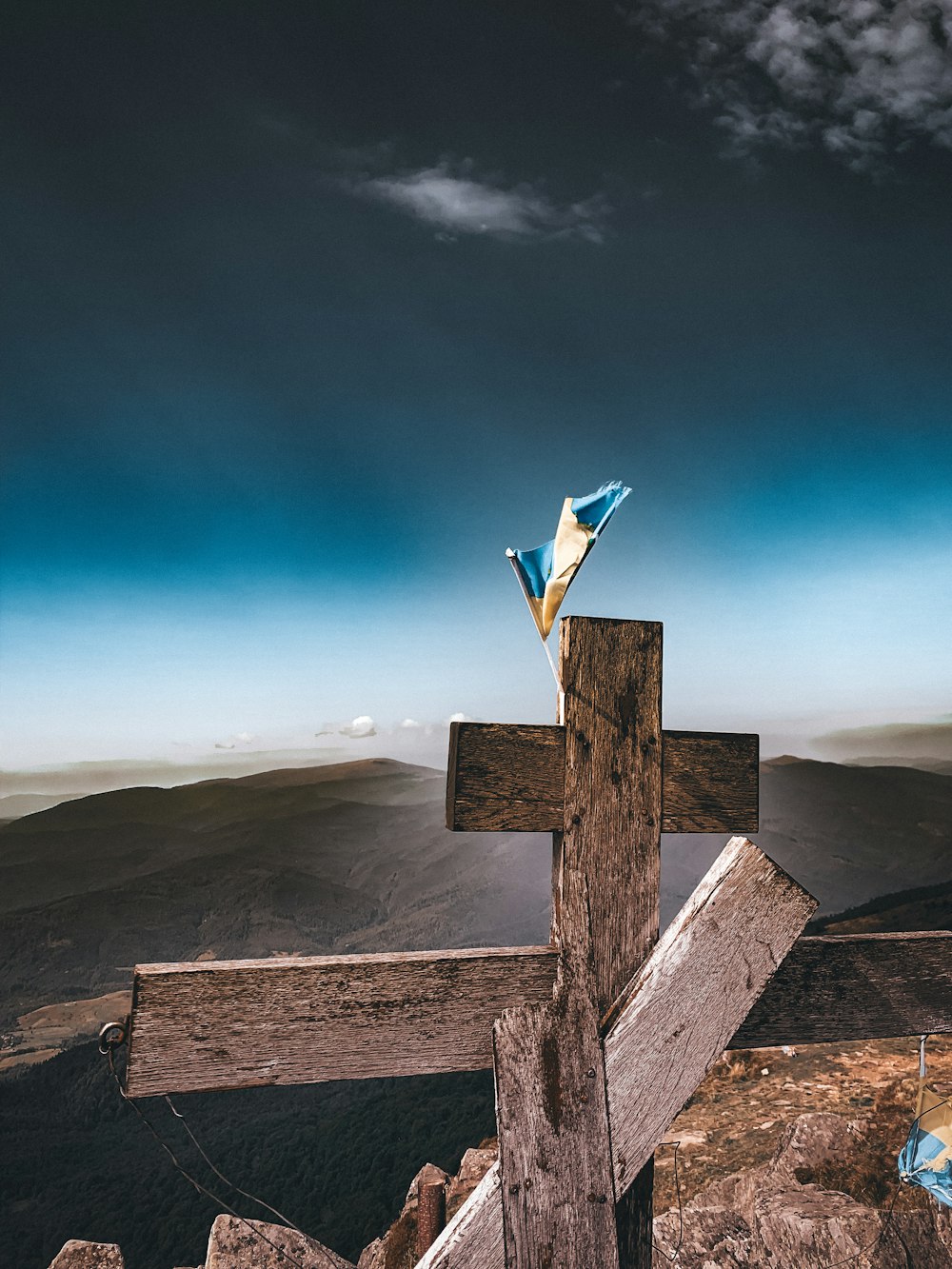 a wooden cross on top of a mountain under a cloudy sky