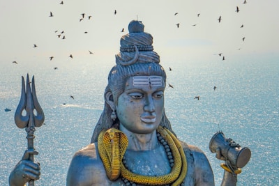 a statue of a hindu god with birds in the background