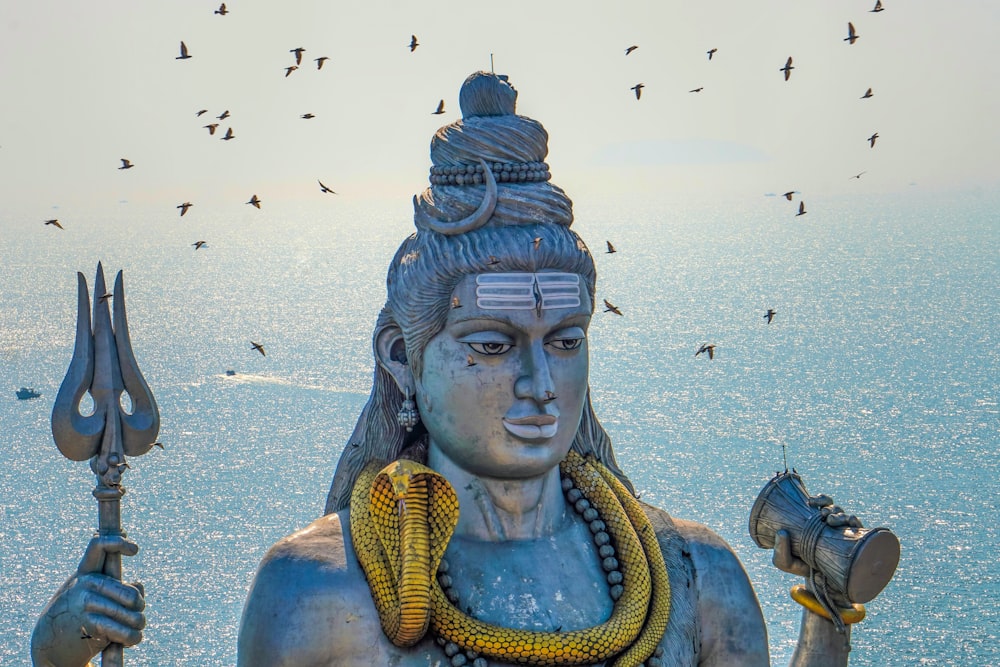 Eine Statue eines hinduistischen Gottes mit Vögeln im Hintergrund
