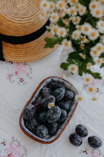 A tiny cotton cap resting on a rustic Himalayan wooden table beside fresh mountain flowers.