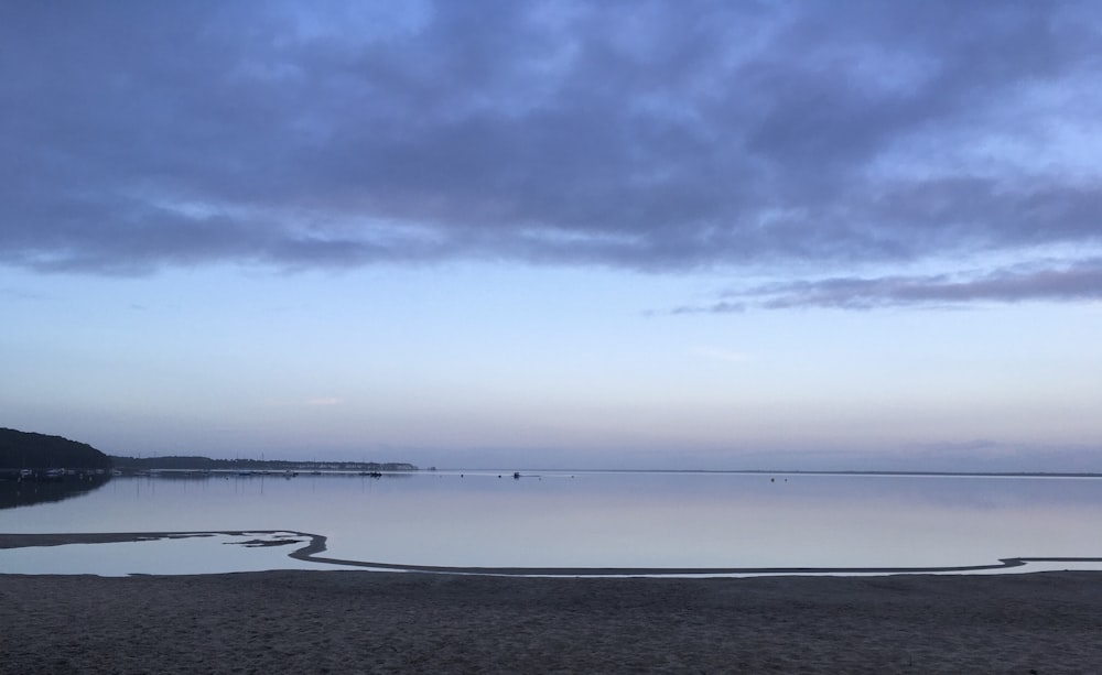 a large body of water sitting under a cloudy sky