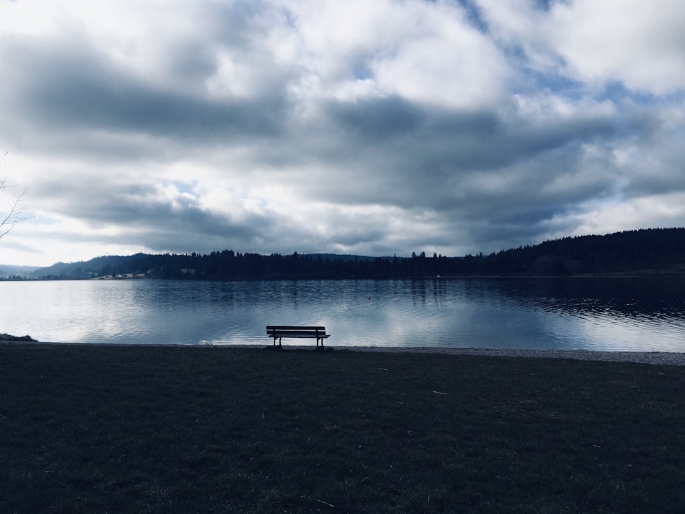 a bench sitting on the shore of a lake