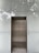 An elevator with metallic doors is set into a modern exterior with frosted glass panels. The reflection of surrounding trees and a building is faintly visible on the glass, giving a somewhat ethereal appearance.