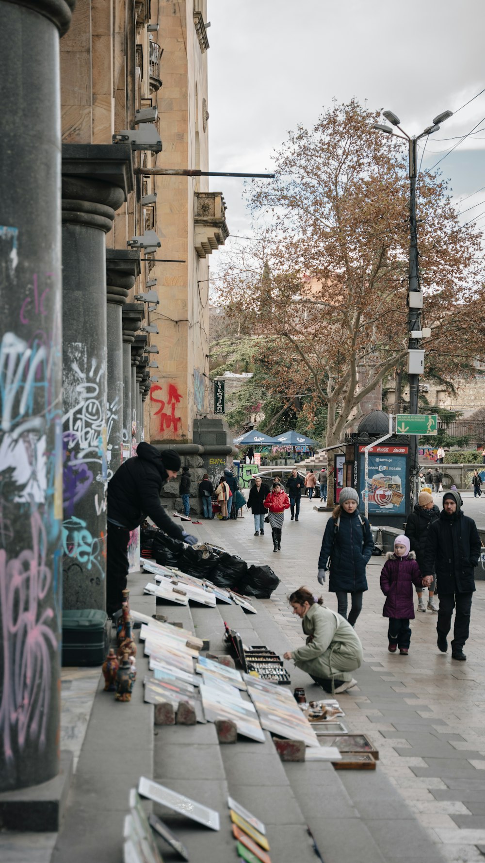 a group of people walking down a street next to a sidewalk