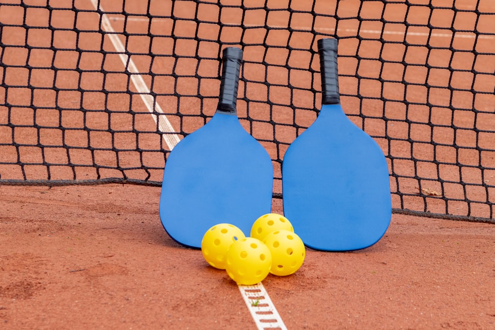 two paddles and three balls on a tennis court