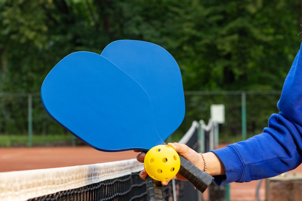 a person holding a tennis racket and a ball