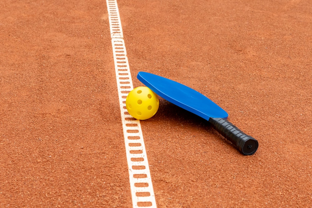 a tennis racket and ball on a clay court