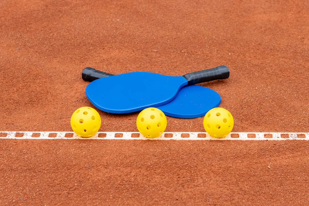 two paddles and three balls on a tennis court