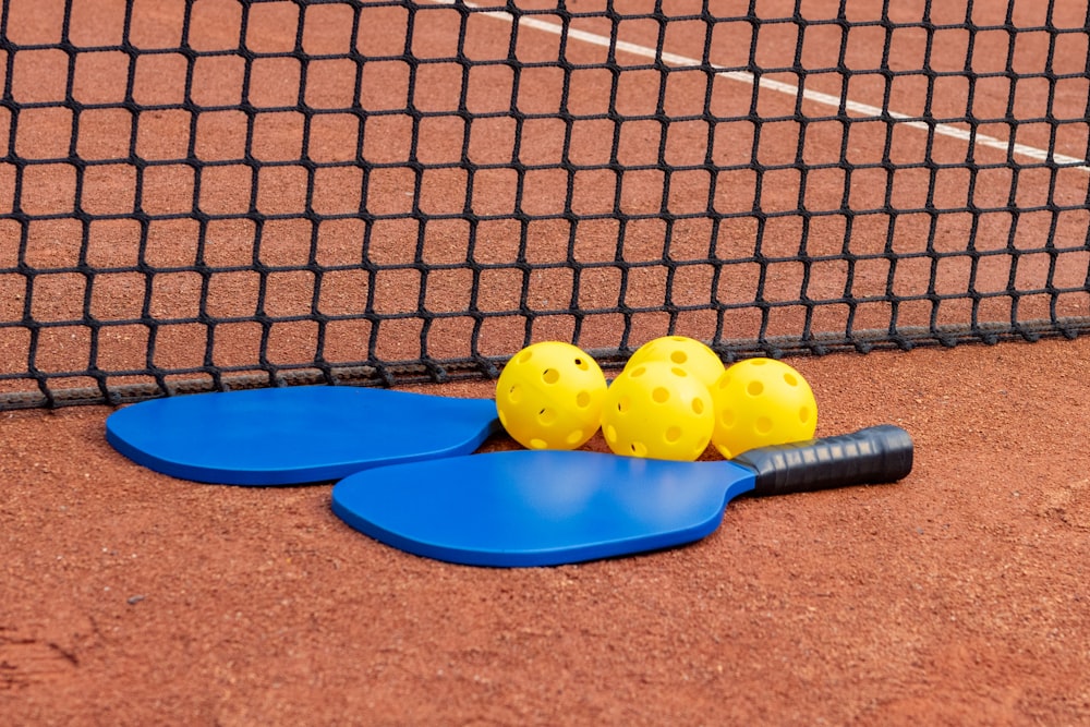 a tennis racket and three tennis balls on the ground