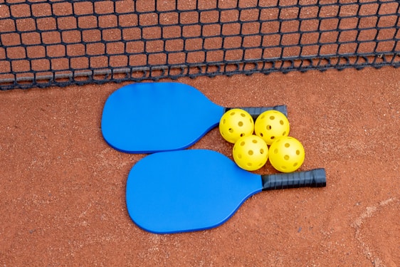 three paddles and three balls on a tennis court