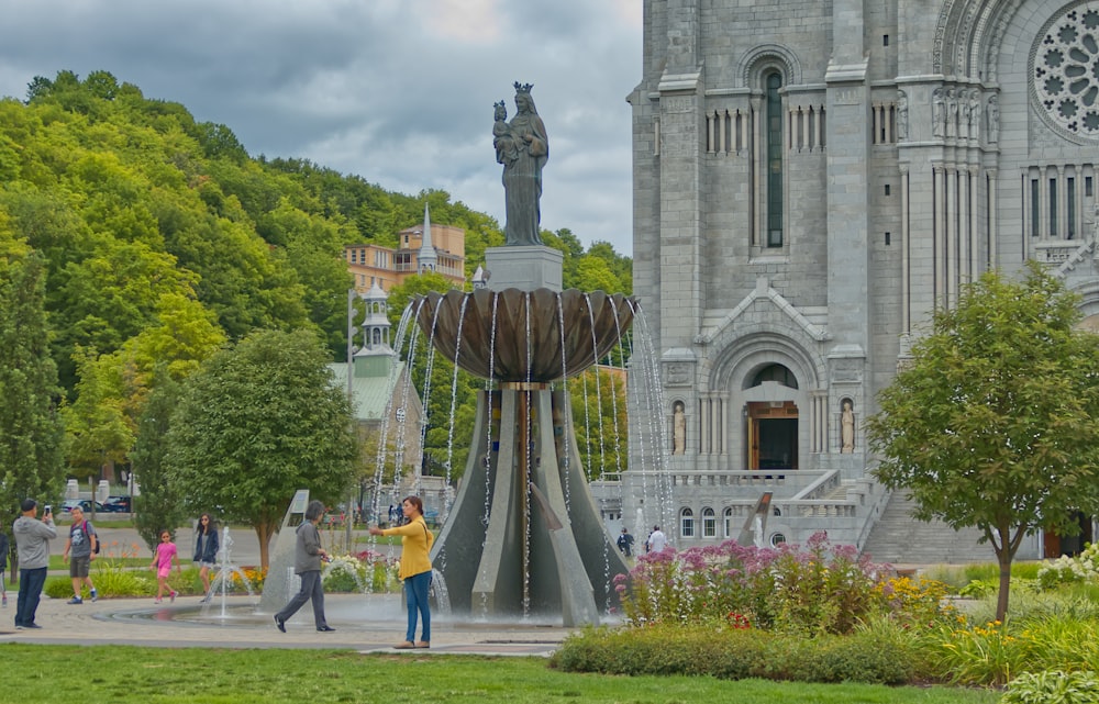 a group of people standing around a fountain in front of a church