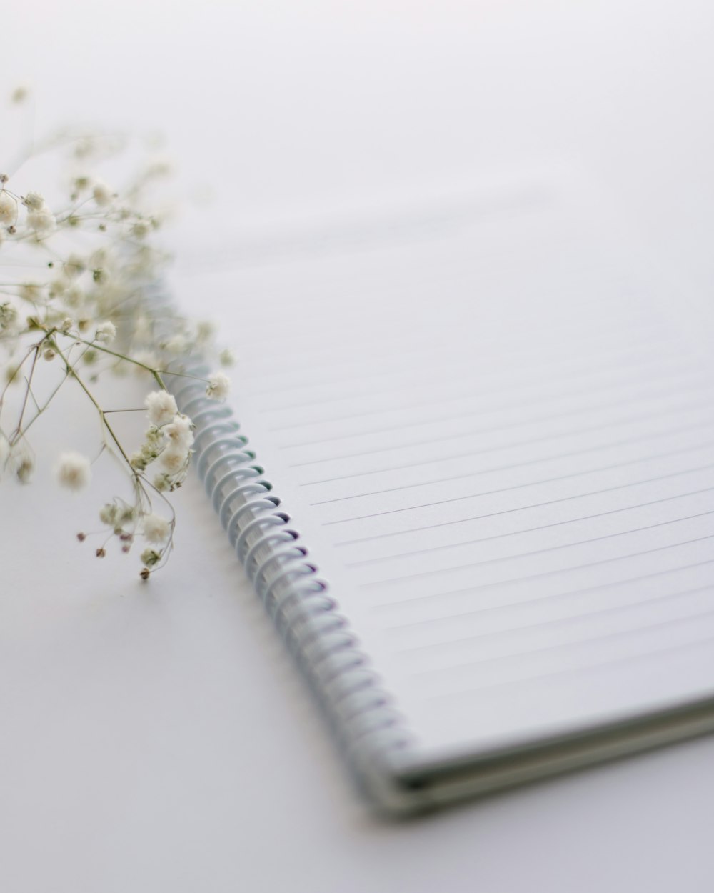 a notebook with a pen and a flower on a table