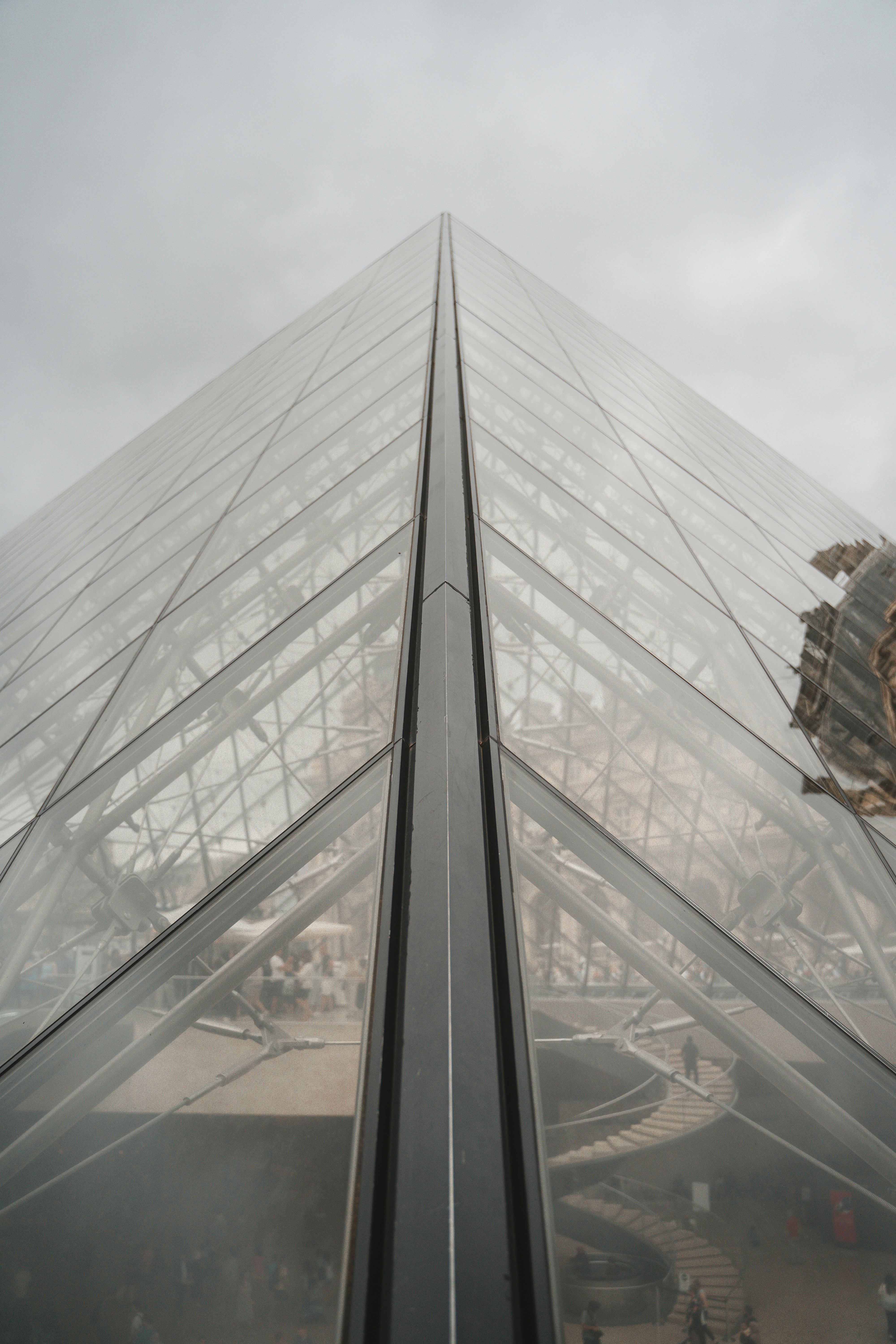a very tall glass building with a clock on it's side