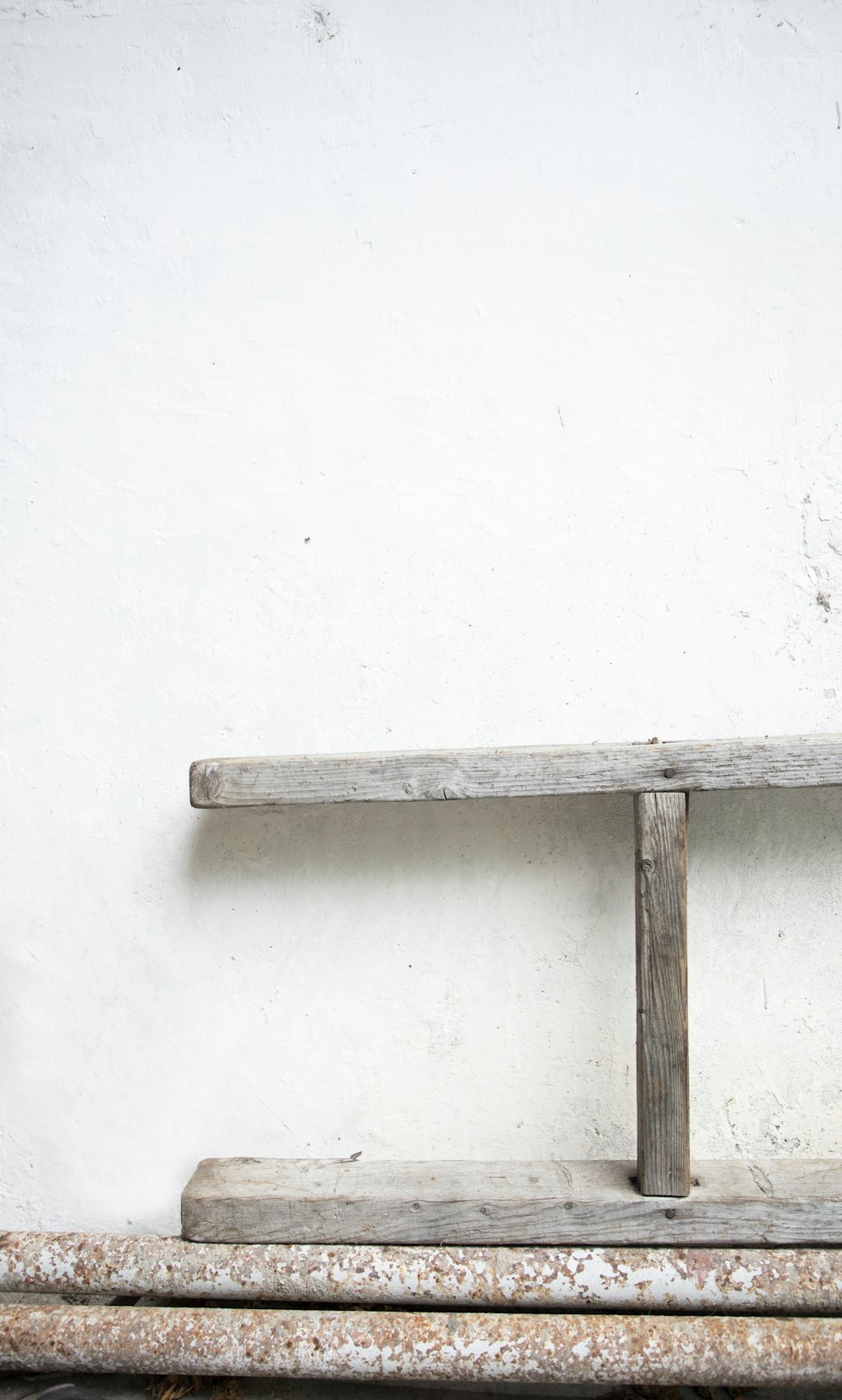 a wooden bench sitting next to a white wall