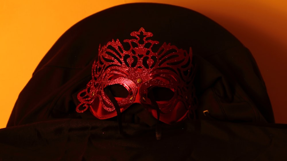 a red mask sitting on top of a black jacket