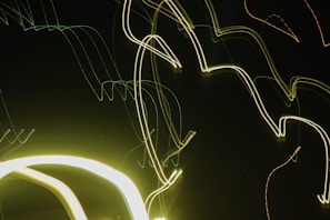 Intersecting and curved neon light trails against a dark background, creating an abstract and modern visual effect.
