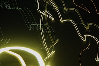 Intersecting and curved neon light trails against a dark background, creating an abstract and modern visual effect.