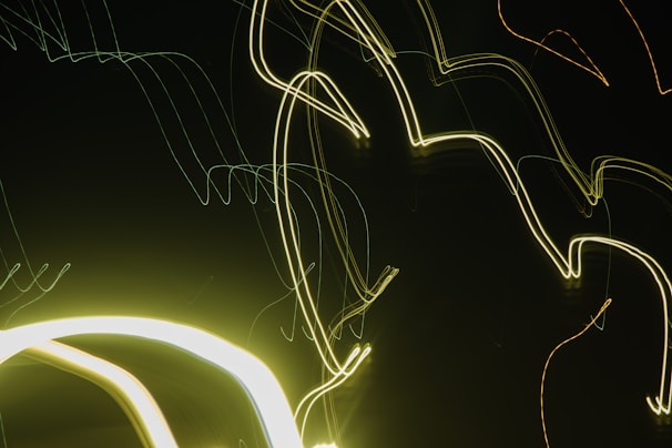 Intersecting and curved neon light trails against a dark background, creating an abstract and modern visual effect.