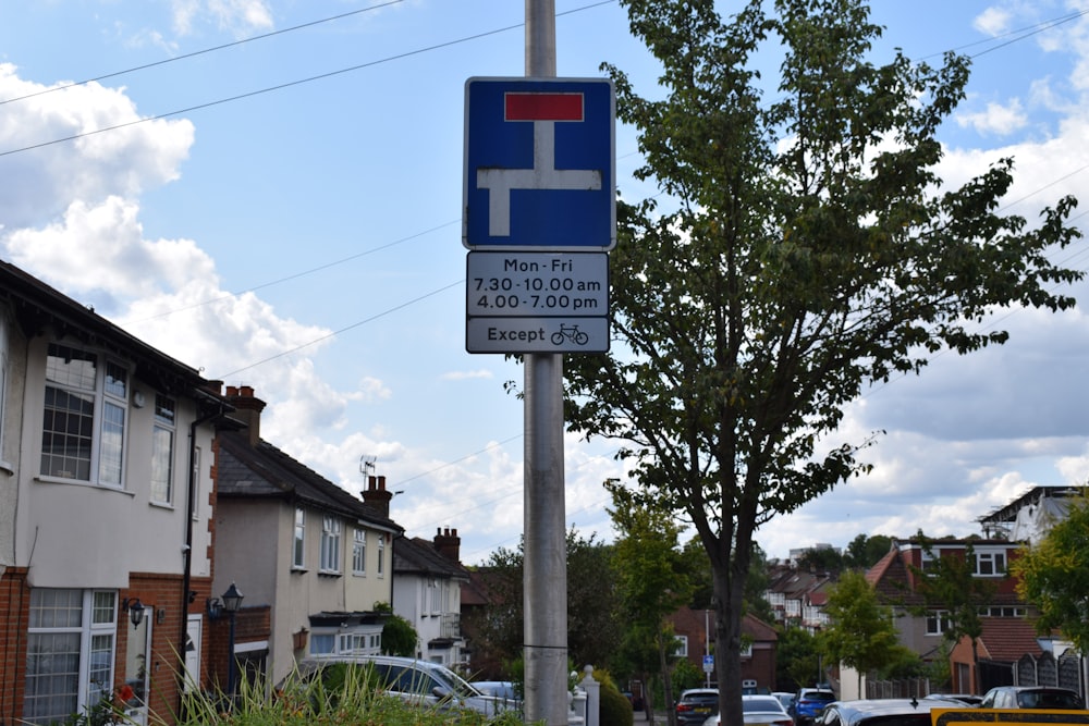 a parking sign on a pole in front of a row of houses