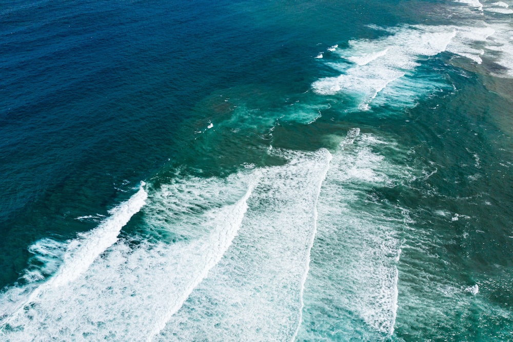 an aerial view of the ocean with waves crashing on the shore