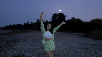 A joyful woman standing tall with arms raised towards the sunrise.