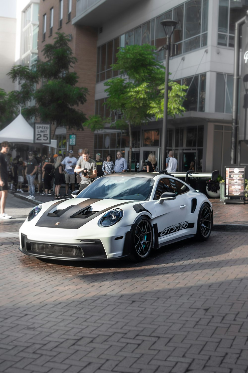 a white sports car driving down a street next to a tall building