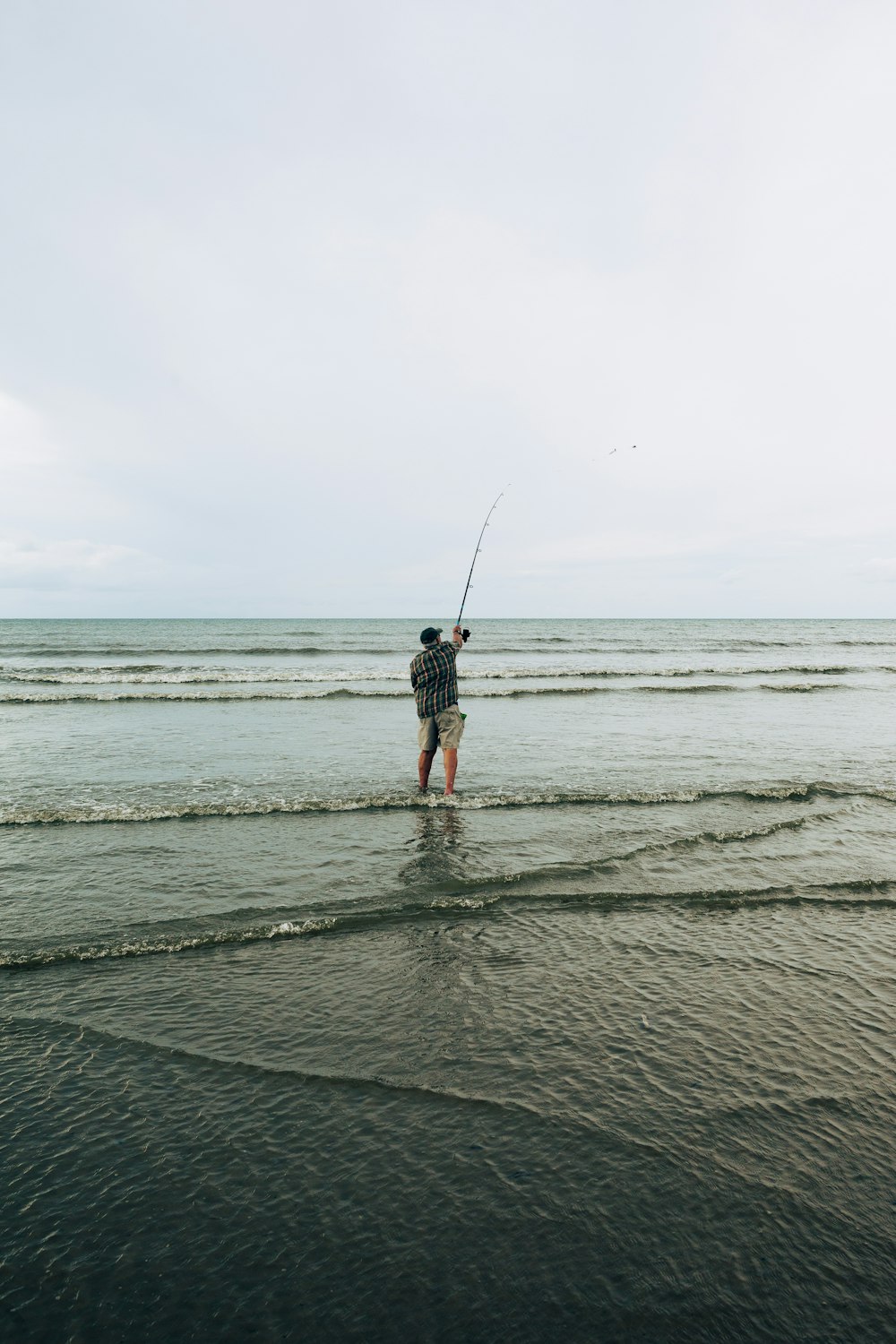 a man standing in the ocean holding a fishing rod