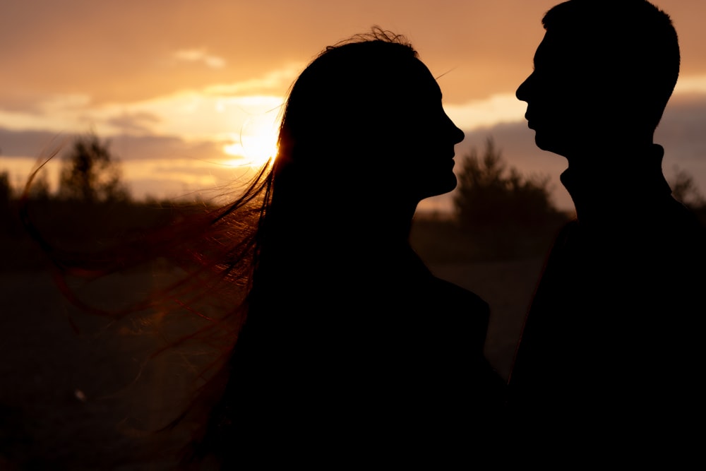 a man and a woman are silhouetted against a sunset