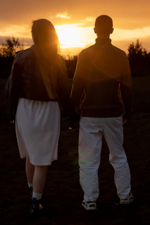 A joyful couple holding hands under a sunset sky with navy blue and orange hues.