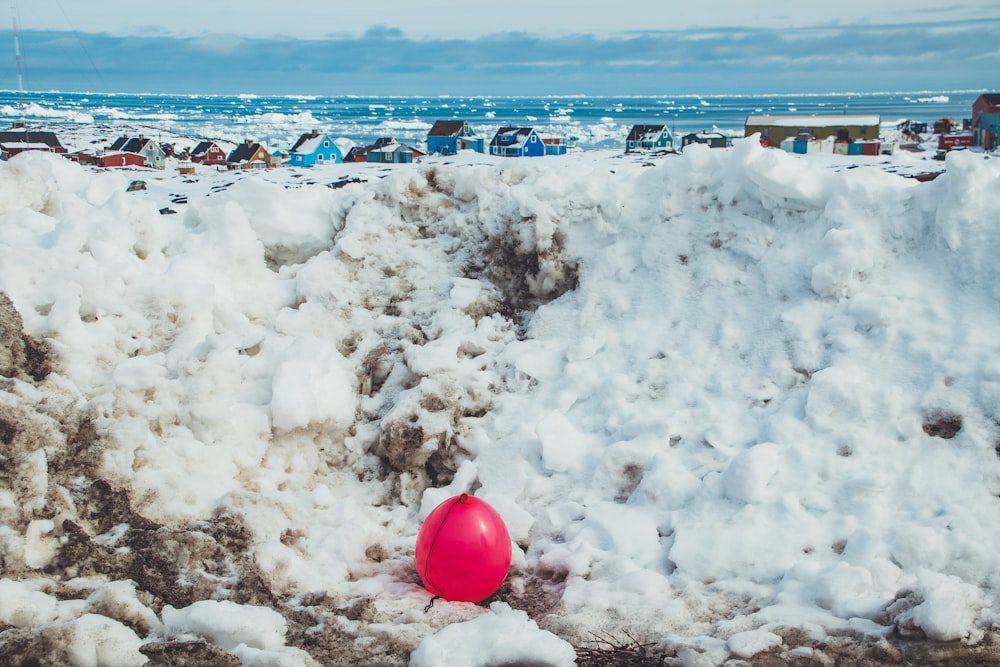 a red ball sitting on top of a pile of snow
