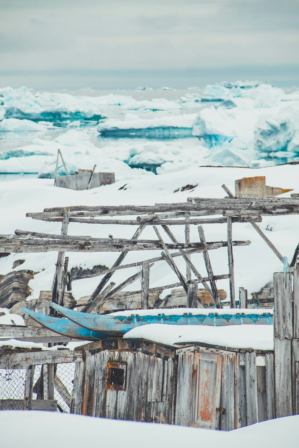 an old wooden structure in the snow with ice behind it