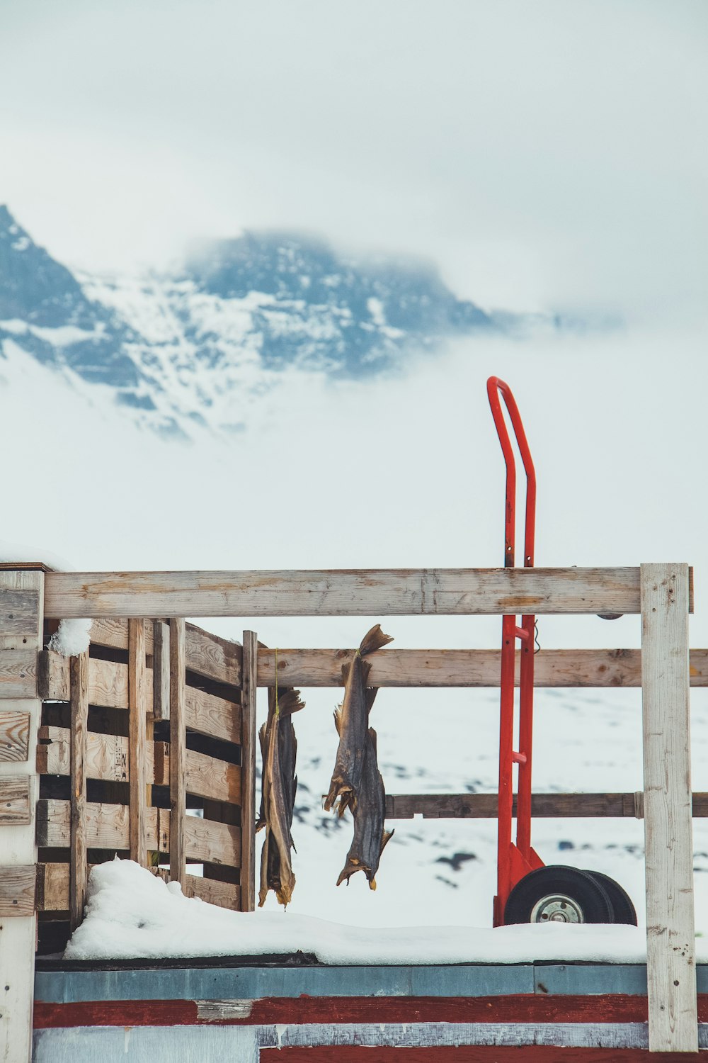 a wooden fence with a red pole and some snow