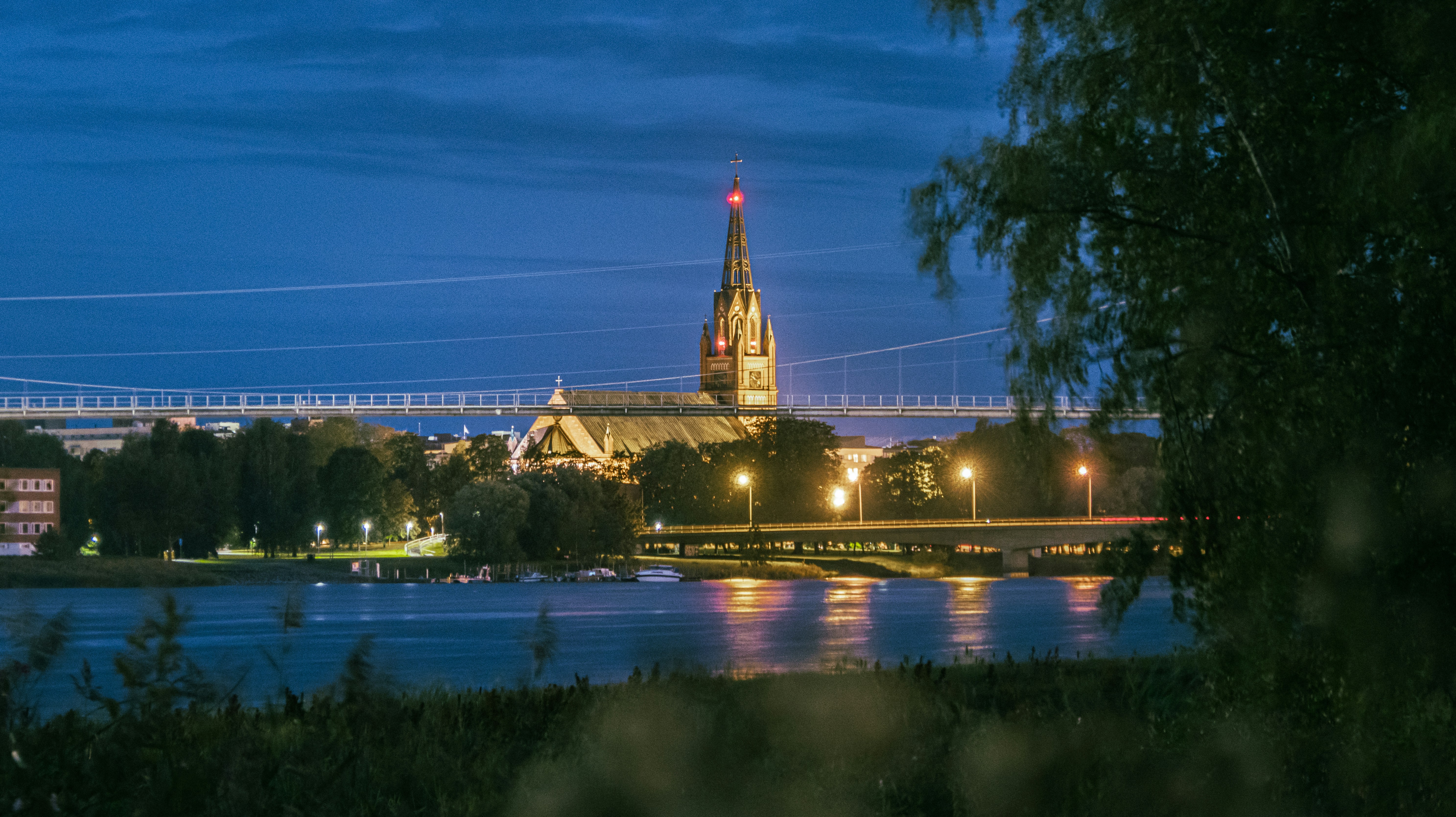 a view of a city at night from across a river, Walking at the River Kokemäki at late August evening.