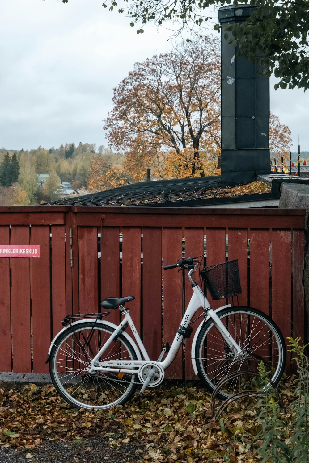 a white bicycle leaning against a red fence