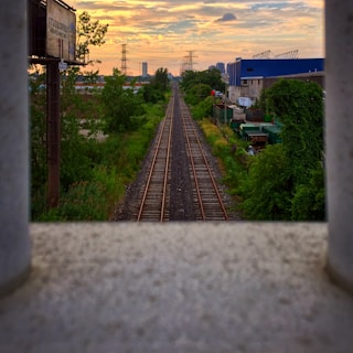 Railway tracks stretching into the distance with overhead electrification structures, captured during golden hour.