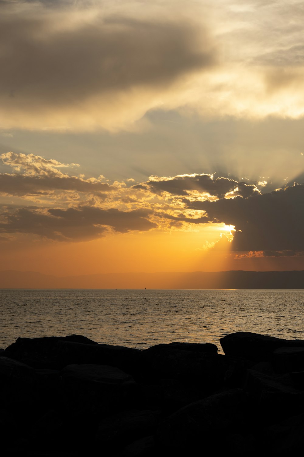 the sun is setting over the ocean on a cloudy day