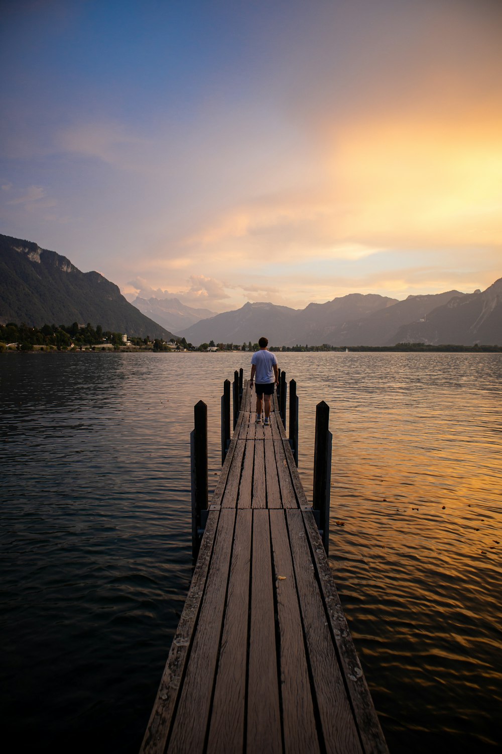 Una persona in piedi su un molo nel mezzo di un lago