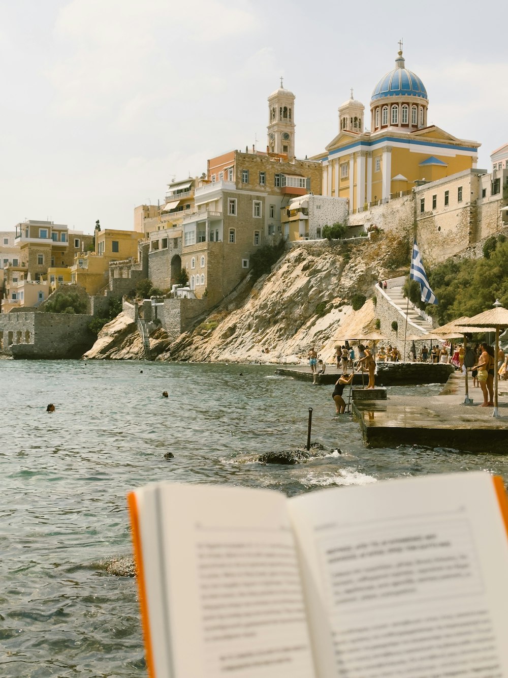 ein aufgeschlagenes Buch, das auf einem Strand neben einem Gewässer sitzt