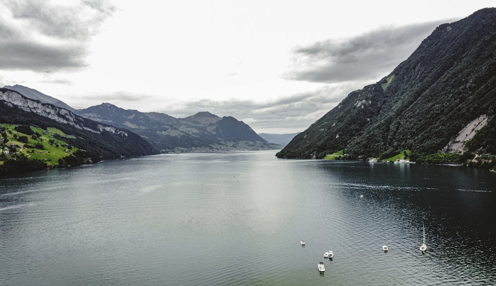 a body of water surrounded by mountains under a cloudy sky